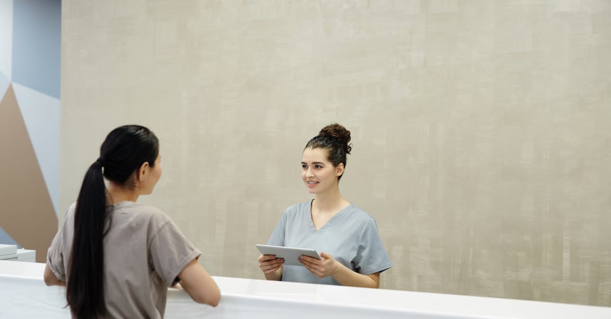 Clinic receptionist using a tablet with clinic management software at a modern front desk.